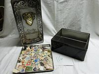 Two metal storage tins with assorted vintage canceled postage stamps inside one tin.