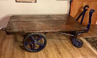 Side view showing aged wooden top and large fixed cast iron wheels