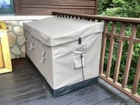 Front and side view of entire patio storage box showing canvas cover, straps, and placement on deck.