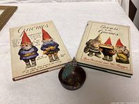 Two vintage gnome books with illustrated covers alongside a small ceramic bowl decorated with a gnome figure.