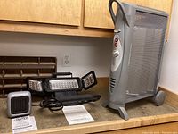 Photo showing Bionare electric heater, LED folding work light, Honeywell Handy Heater and instruction manuals on a wooden counter.
