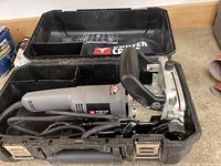 Porter Cable electric joiner inside its hard plastic carrying case featuring compartments and latches.
