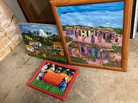 Three village life paintings including one large framed, one medium canvas, and one small red-framed canvas.