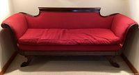 Front view of the loveseat showing the carved wood frame and red fabric cushions.