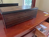 Exterior view of rectangular dark wood box with keyhole on front