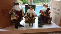 Three Crakewood Santas displayed on a window ledge showing all items and their original boxes.