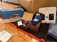 Overview of lot showing Ring battery pack box, Canon camera box and charger, Atomi mini power bank pack, blue corded phones on moving blanket