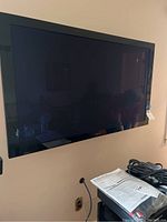 Front view of Elite 50 inch flatscreen television mounted on wall showing screen and surrounding area.