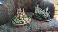 Two castles on patterned fabric couch: Neuschwanstein on right with blue spires, Camelot on left with colorful turrets