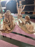 Two Lladro porcelain figurines of children with pets displayed on a glass table