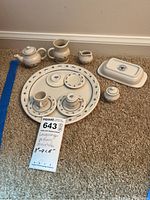 Photo showing all pieces arranged on the carpet including teapot, creamer, sugar bowl, butter dish, several plates, saucers, cups, and tray.