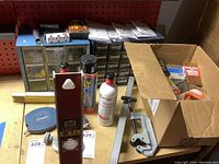 Full lot view showing organizers, level, pipe cutter, spray cans, tape measures, and a box with small parts.
