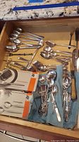 Drawer with a collection of various vintage silverplate spoons, forks, and boxed WMF teaspoons.