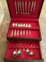 Wooden box open showing red felt–lined upper and lower drawers with flatware pieces