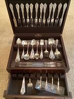 Open wood chest showing two tiers of knives on top and spoons/forks on middle tray