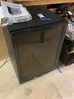 Full view of black wine cellar with glass door and handle, closed, showing overall condition and appearance.