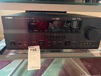 Front view of Yamaha RX-V661 AV receiver showing the full control panel and model details with the remote control visible.