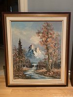 Full view of larger framed acrylic landscape painting showing mountainous scenery with river and trees.