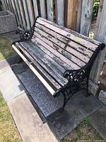 Front and side profile showing overall bench, wooden slats, and black cast iron armrests and legs.