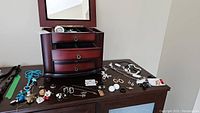 Jewelry and wooden jewelry box with necklaces, earrings, brooches spread on table
