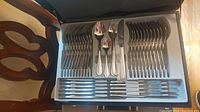 Complete set of flatware in a storage case showing forks, spoons, knives, and serving utensils.