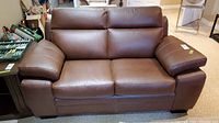 Front view of brown leather loveseat showing seat cushions and backrests