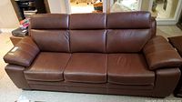 Front view of brown leather sofa showing all three seats and armrests