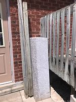 Stack of stone slabs leaning against brick wall alongside two wooden posts