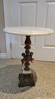 Full view of round marble top, ornate column with cherubs and square base