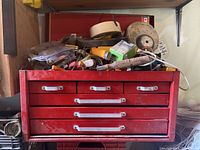 Closed red steel toolbox with four drawers and silver handles showing some wear.