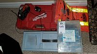 Milwaukee hammer drill in red case with charger and rainwear on top