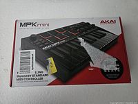 Box of AKAI MPK Mini MIDI controller showing model, branding, and some text.