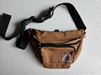 Full view of the brown Carhartt fanny pack showing its shape and adjustable black strap.