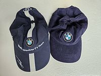 Top view showing both navy blue caps side by side, one with BMW Sauber F1 Team branding and one with BMW logo