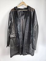Black RAINS men's raincoat jacket hanging on a hanger, front view showing full length, hood, and snap button closure.