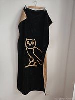 Full view of towel hung up showing black side with tan owl design.