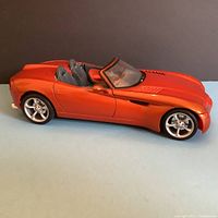 Side profile of orange Maisto 1:18 scale Dodge Copperhead diecast model car showing detailed body shape and interior seats.