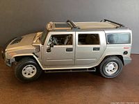 Side view of silver diecast Hummer model showing doors, tires, and roof rack.