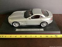 Side view of silver Mercedes-Benz SLR McLaren diecast model on black display stand with ruler measuring length about 11 inches