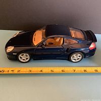 Side view of the dark blue Porsche 996 diecast model with tan interior, measuring approximately 9 inches in length, showing open driver's door.
