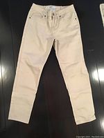 Front view of beige ladies jeans showing narrow leg, front pockets, button, and zipper.