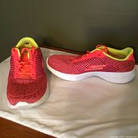 Photo showing side and front view of bright red Skechers GOGA MAX ladies runners with neon yellow lining and orange laces, white sole.