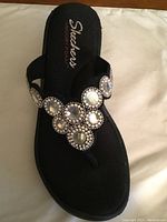 Close-up top view of black Skechers sandal showing crystal decorations and Skechers memory foam footbed.