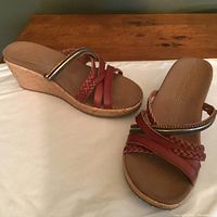 Pair of women's Skechers dark tan strappy sandals with cork wedge heels on a flat surface, showing braided and beaded strap details.