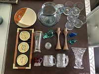 Top view of lot items including glass pitcher, glasses, candlesticks, animal figurines, ashtray, mugs, vases, decorative plates and ceramic dish
