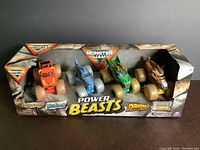 Front view of the Monster Jam Power Beasts 4 pack in original packaging showing all four trucks inside.