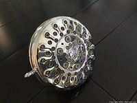 Photo of the Moen chrome shower head showing its circular nozzle pattern and adjustment lever