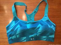 Front view of teal Under Armour sports bra showing geometric pattern and adjustable straps