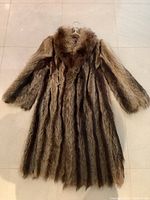 Front view of knee-length raccoon fur coat showing long fur stripes and wide collar.