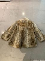 Top view of the front of the vintage fur coat laid flat to show natural fur texture and color tones.